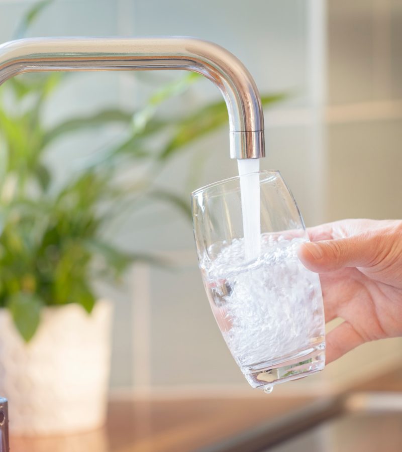 Filling up a glass with clean drinking water from kitchen faucet